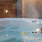 Modern outdoor hot tub at dusk with steam rising and a hand holding a spa pH test strip above clear water, illustrating spa pH adjustment and balanced water chemistry.